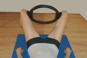 esercizio per il bacino  con un cerchio di pilates tra le gambe